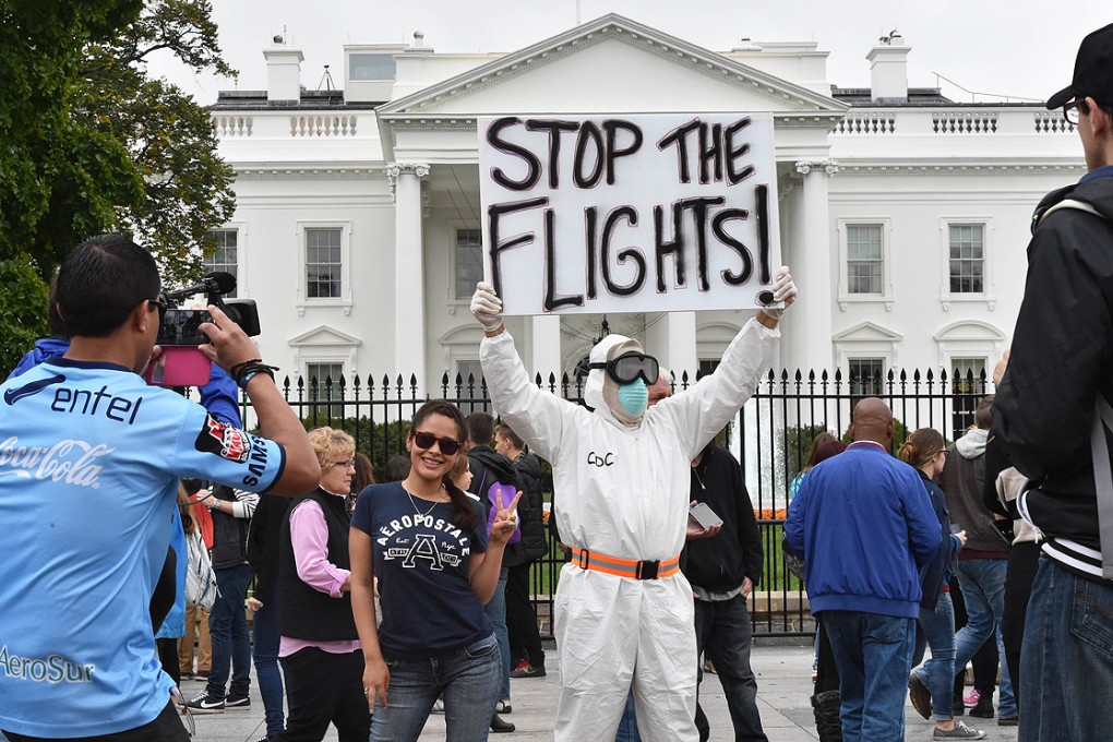 A tourist poses next to Jeff Hulbert from Annapolis, Maryland, dressed in a protective suit and mask demanding for a halt of all flights from West Africa, outside the White House in Washington on Thursday. Photo: AFP