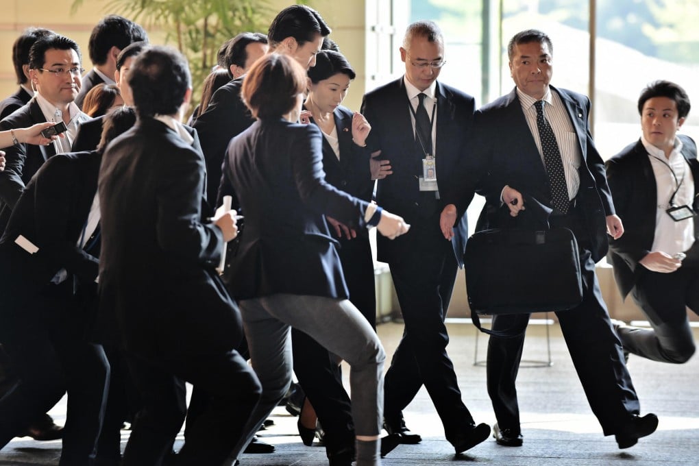 Reporters mob Yuko Obuchi as she arrives at the prime minister's residence to submit her resignation as industry minister. Photo: AFP