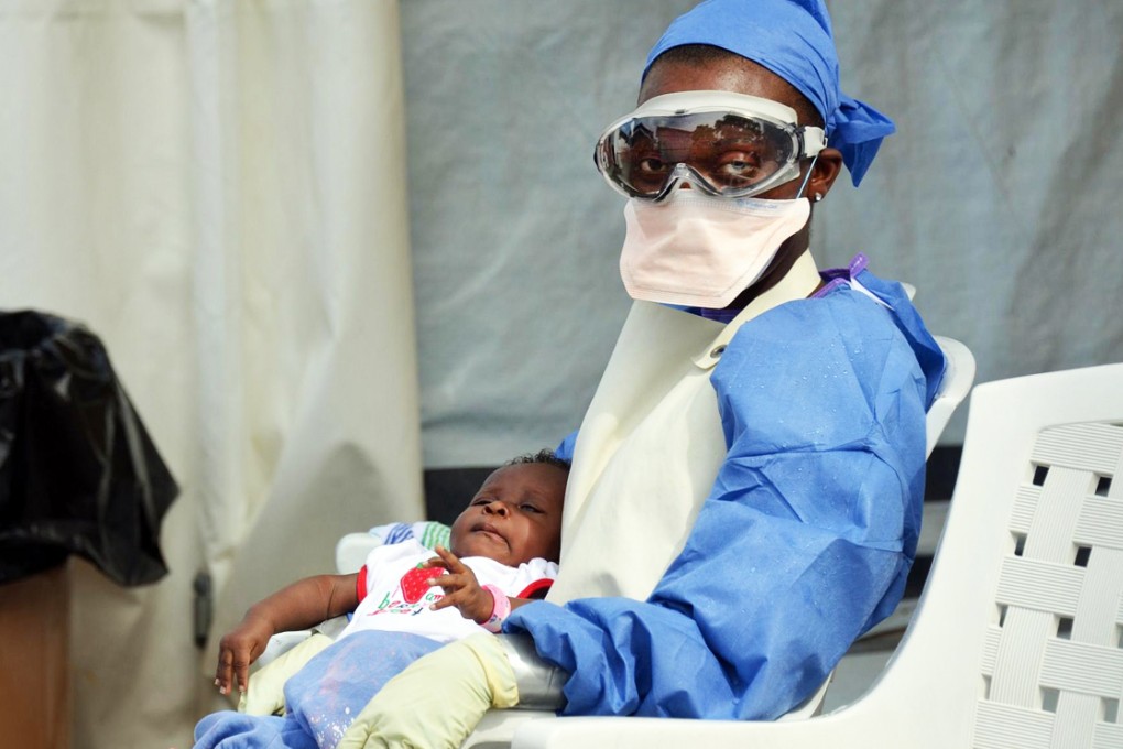 A Liberian nurse holds a baby infected with Ebola. Photo: AFP