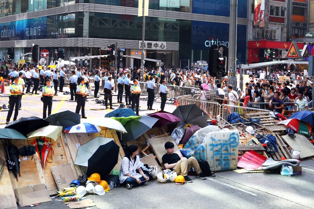 Lines of police standing behind the barricades monitor protesters in Mong Kok on Monday. Photo: K.Y. Cheng