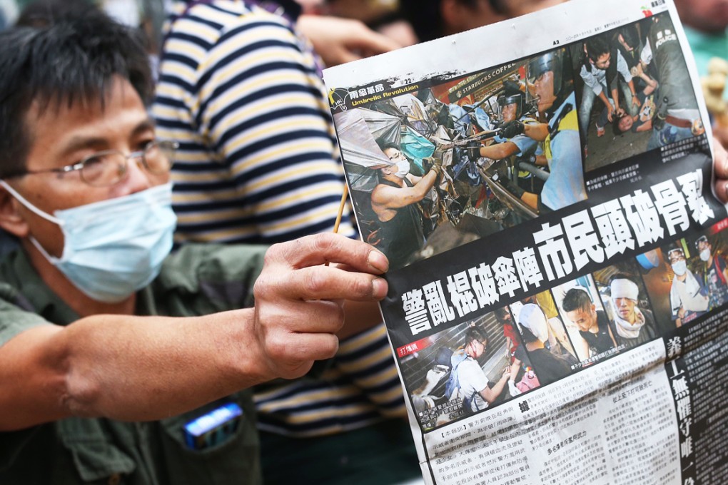 A protester shows police a newspaper report on last night's violence. Photo: K.Y. Cheng
