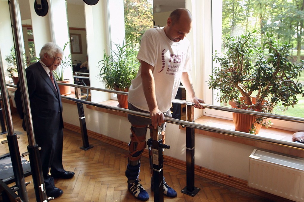 Professor Wagih el-Mastri looks on as once-paralysed Darek Fidyka walks with help. Photo: AFP