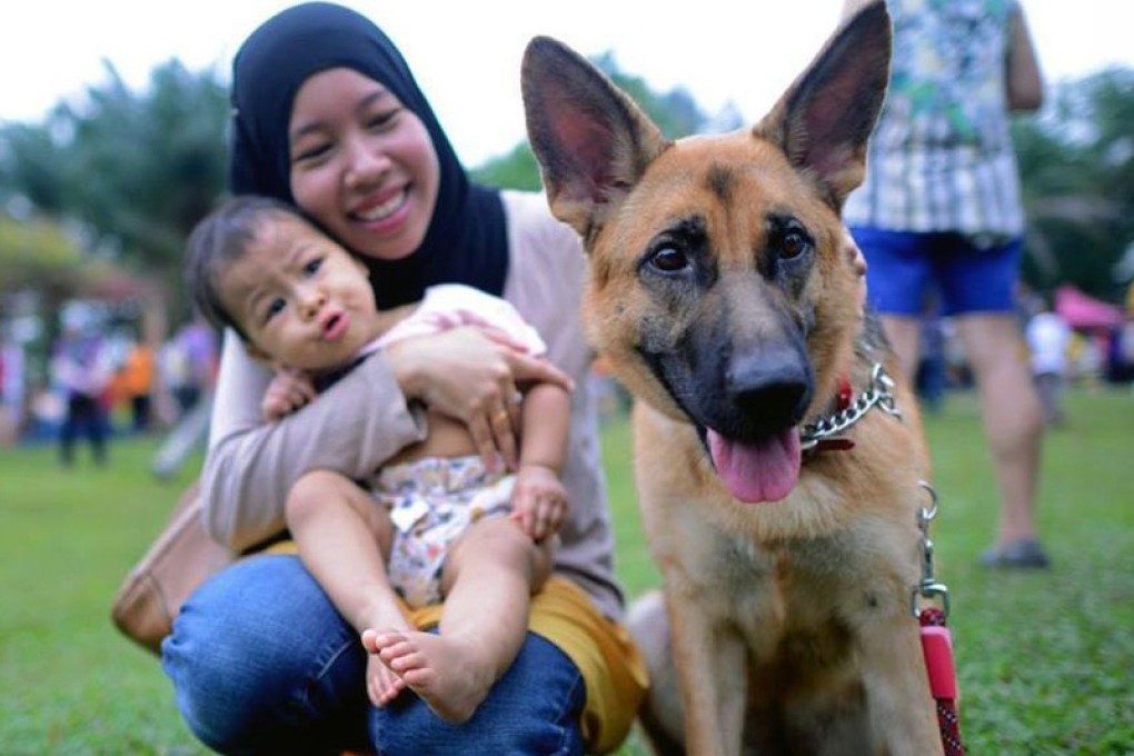 A Muslim mother and her baby girl get close to a dog during the 'I Want To Touch A Dog' event on October 19, 2014. Photo: Facebook