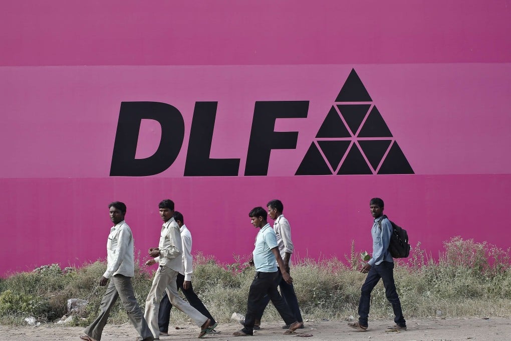 Workers walking past a billboard of DLF Ltd. at Gurgaon on the outskirts of New Delhi. Photo: Reuters