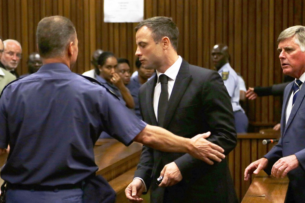 Oscar Pistorius (centre) is led by officer into a holding cell after being sentenced at the high court in Pretoria. Photo: AFP