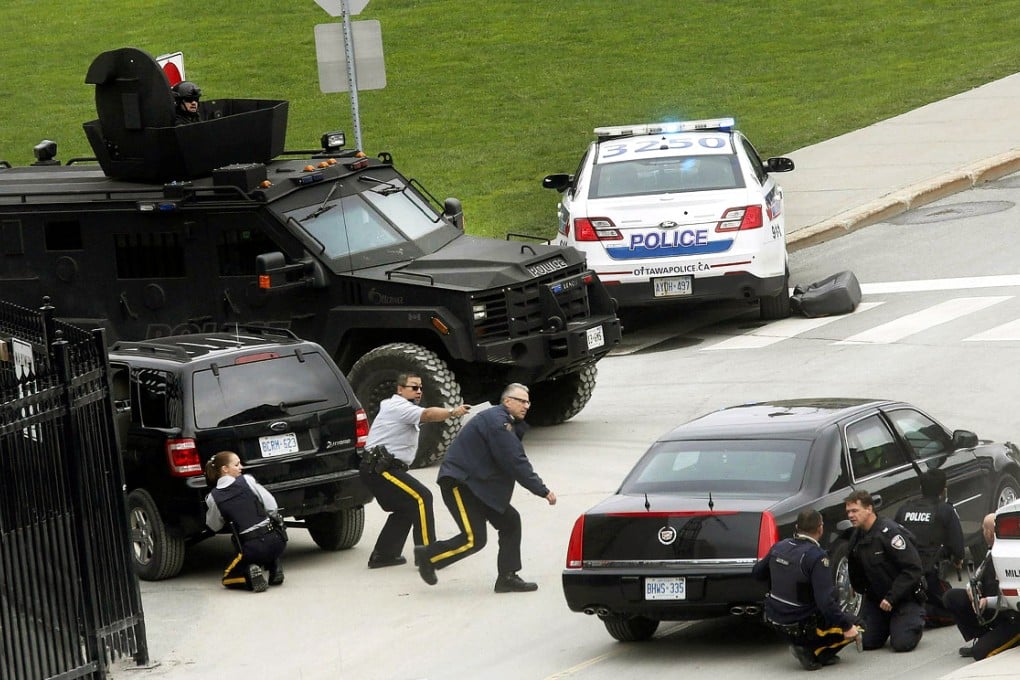 Police officers take cover near Canada's parliament in Ottawa yesterday after a gunman who shot dead a soldier standing guard at the nation's war memorial stormed into the building. Photo: Reuters