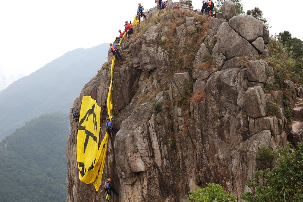 Firemen remove the banner off Lion Rock at 1pm. Photo: Robert Ng