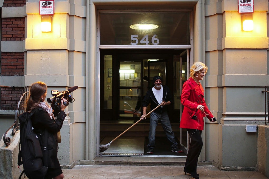 A man mops the entrance of Doctor Craig Spencer's building while a journalist exits, before it was confirmed he had contracted Ebola in New York. Photo: Reuters