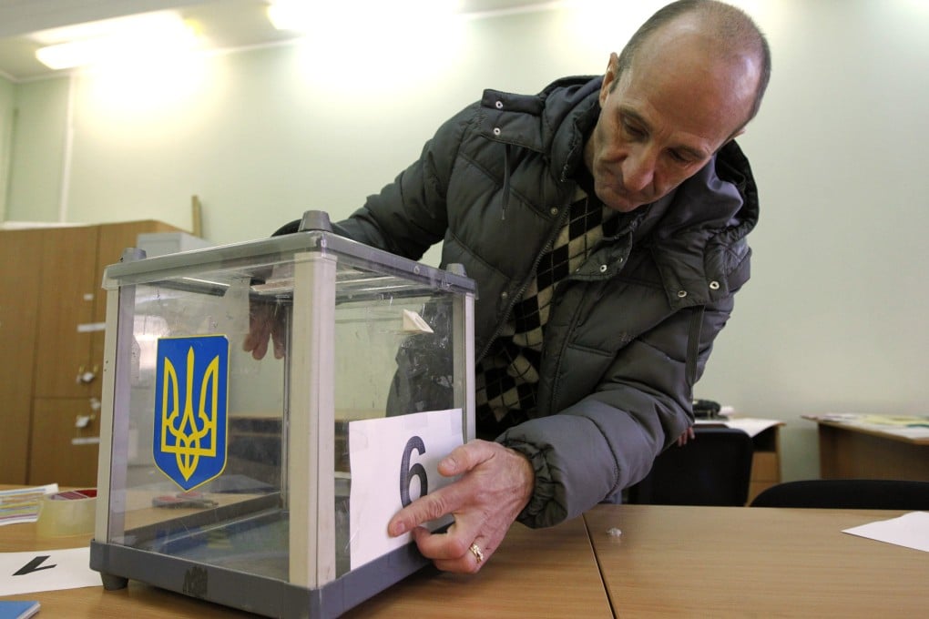 An election commission worker adjusts a number on a ballot box at a polling station in Kiev. Photo: Reuters