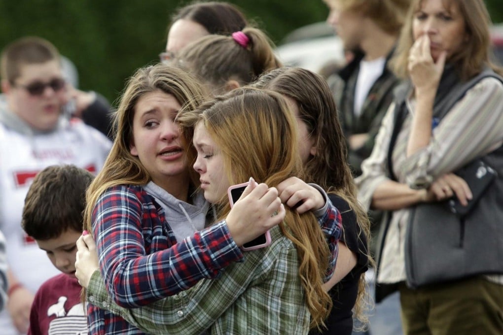 Two girls share a hug outside a church where families were reuniting after the shooting in Marysville, Washington, on Friday. Photo: Reuters