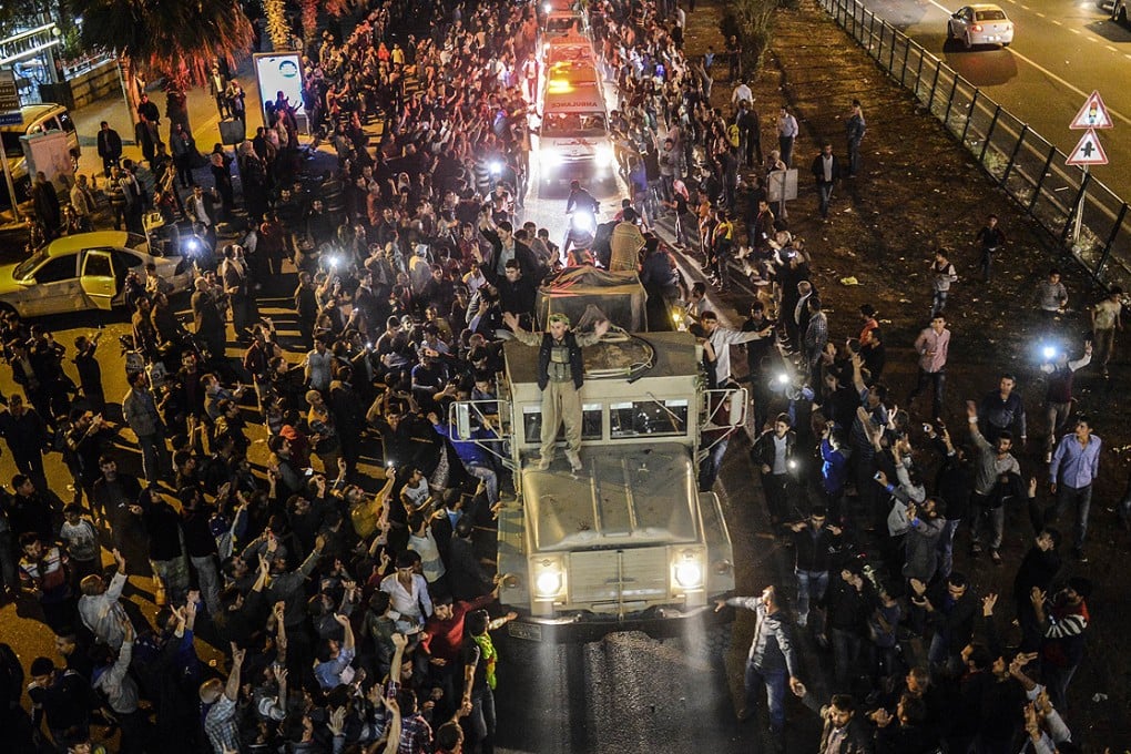 Kurds in Turkey greet peshmerga troops travelling in a convoy towards the Syrian border town of Kobane on Wednesday. Photo: AFP