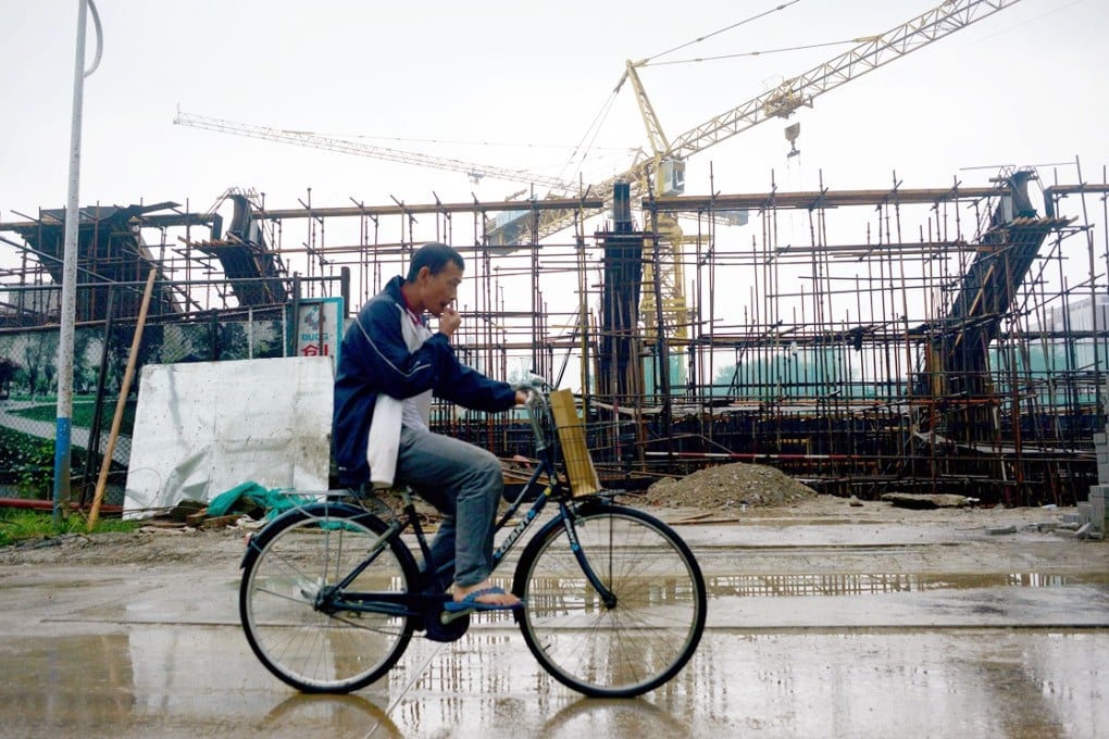 A man rides a bicycle past a construction site in Beijing. An effort is under way to tie the capital, Tianjin and Hebei more closely together economically. Photo: AFP