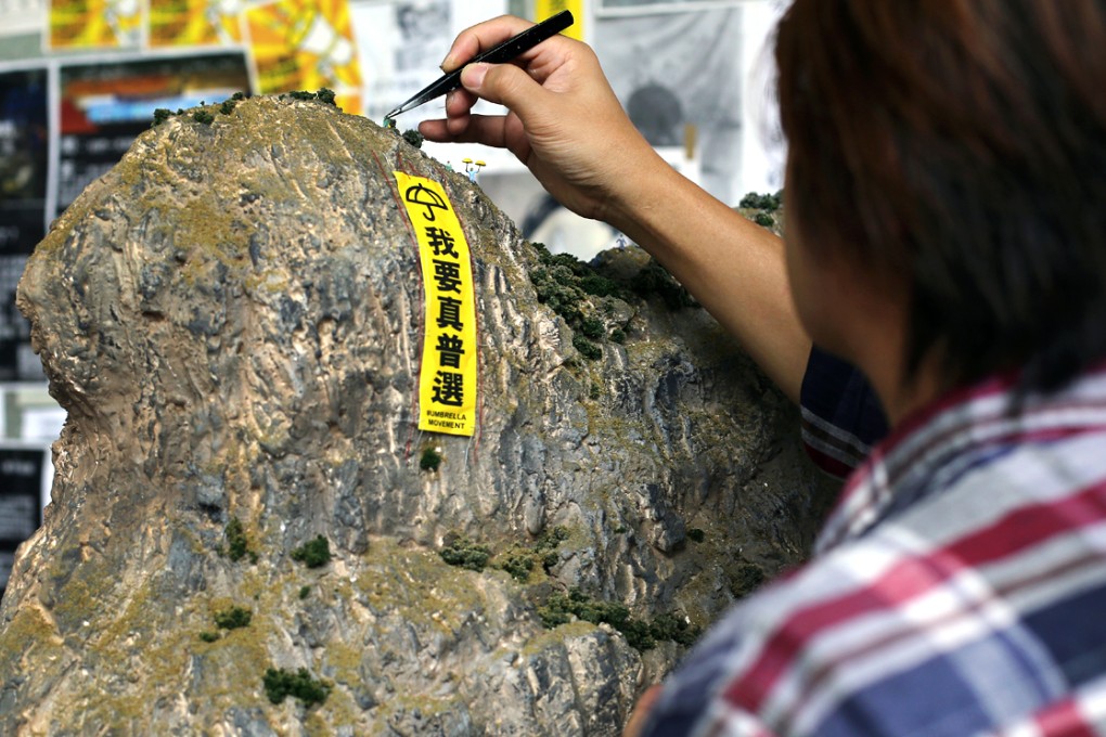 Ray Ng adds the finishing touches to his model of Lion Rock, complete with pro-democracy banner. Photo: Sam Tsang