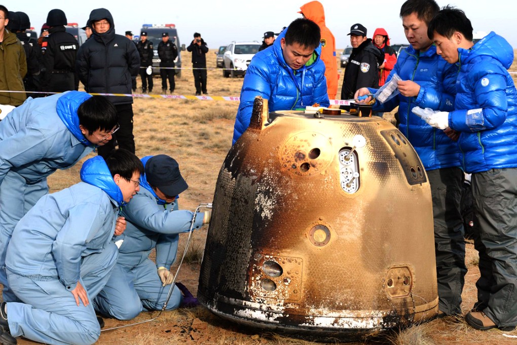 Scientists examine the probe on the Inner Mongolian grasslands. It flew to the moon and then returned to earth. Photo: Xinhua