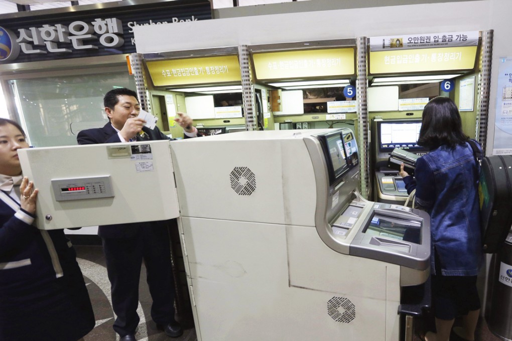 Bank clerks tend an ATM after a cyber attack in Seoul in 2013. Photo: AP