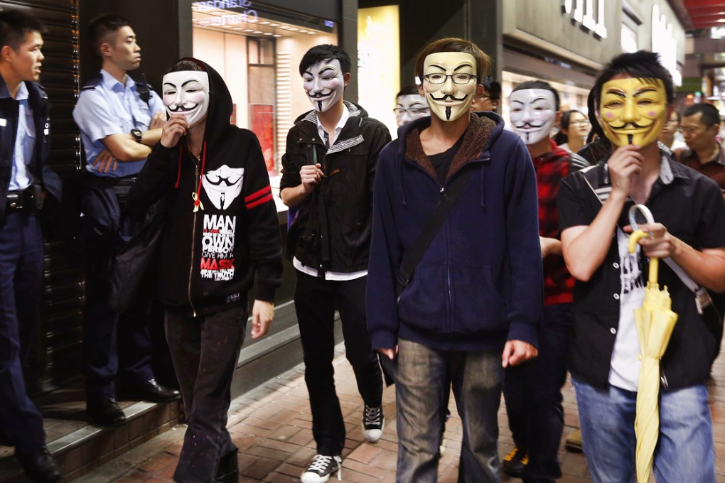 Hong Kong protesters wearing Guy Fawkes masks walk past policemen on a road occupied by protesters as part of the Occupy Central civil disobedience movement at Mongkok shopping district November 5, 2014. Photo: Reuters