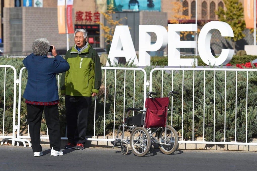 A Beijinger poses in front of a sign promoting the Apec summit. While some see it as their duty to support the event, others are annoyed at the disruption. Photo: AFP