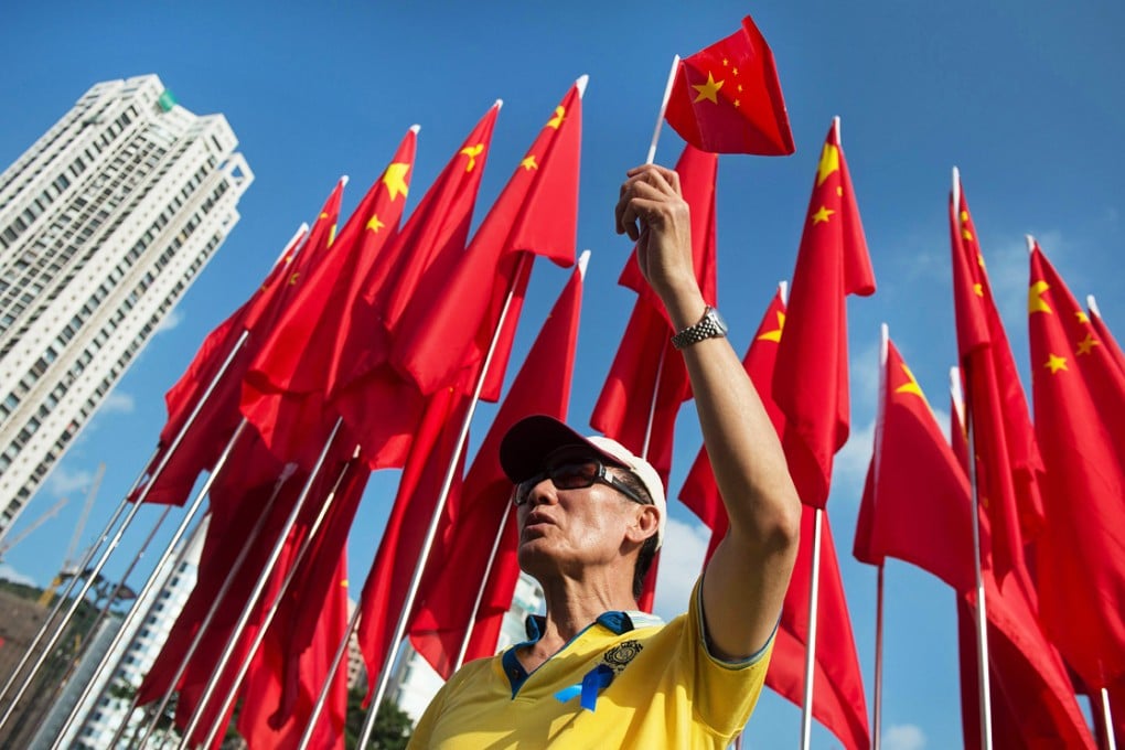 A man holds up a Chinese national flag as he sings the national anthem at an event to celebrate the 65th anniversary of the founding of Communist China at Victoria park in Hong Kong. Photo: AFP