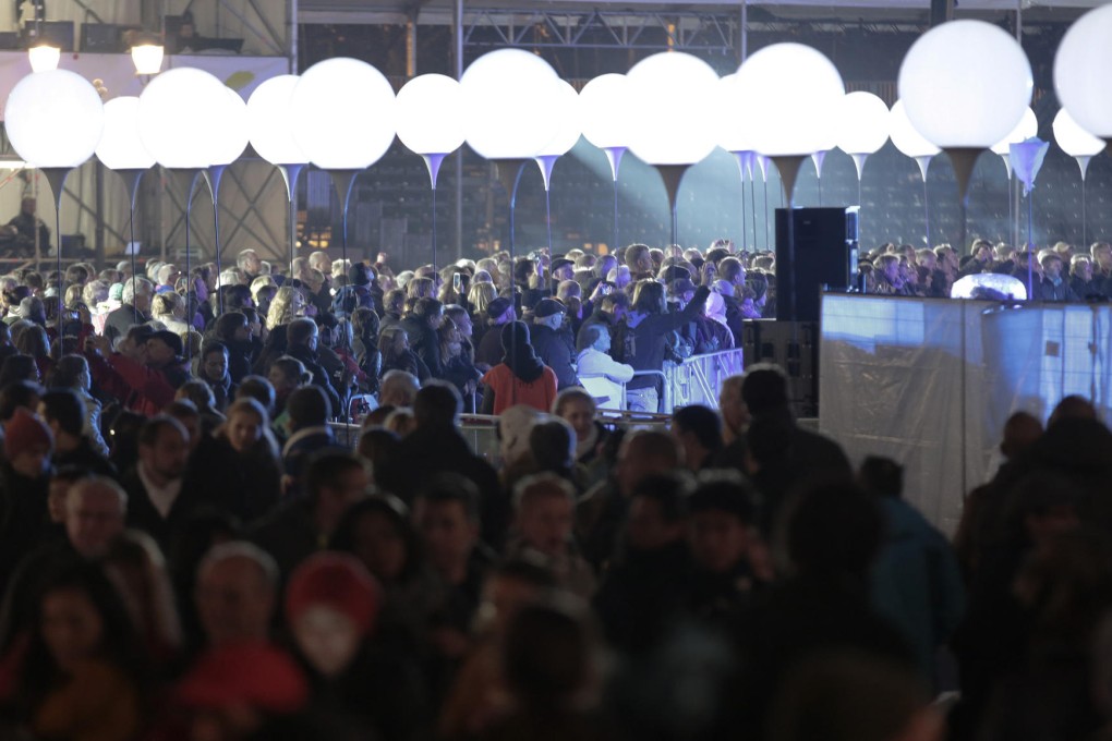 Spectators gather under an art project called "Light Border 2014" - 10km of lights set up on the route of the Berlin Wall. Photo: AP