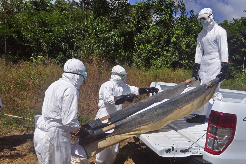 Liberian health workers carry the body of a woman suspected of dying from Ebola at a grave site on the outskirts of Monrovia on Friday. Photo: AP
