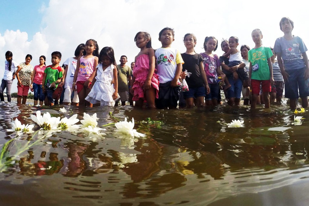 Survivors of Super Typhoon Haiyan in Cavite place flowers into the sea to mark the first anniversary of the disaster, which killed more than 7,300 people when it lashed the Philippines. Photo: Xinhua