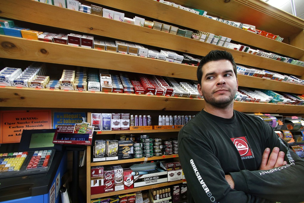Brian Vincent poses in front of a large display of tobacco products at Vincent's Country Store in Westminster, Massachusetts. Photo: AP