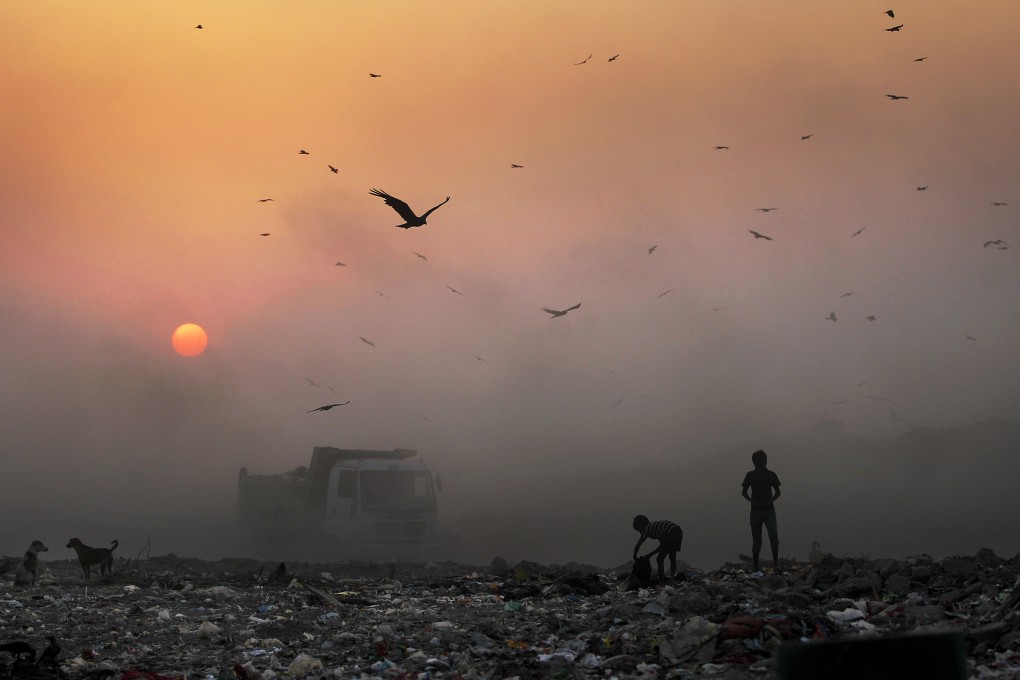 A thick blanket of smoke is seen against the setting sun as young ragpickers search for reusable material at a garbage dump in New Delhi, India on October 17, 2014. Photo: AP