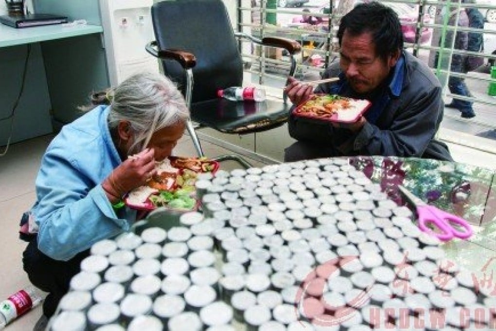 Wang Fang and her husband, Gao Guanglin, enjoy lunch at 
the China Postal Savings Bank in Huangshi as the coins they collected sit on the table. Photo: SCMP Pictures