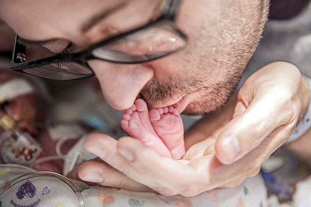 Chris Picco kisses the feet of his baby at the hospital. The video of him singing to the child has been an internet sensation. Photo: SCMP