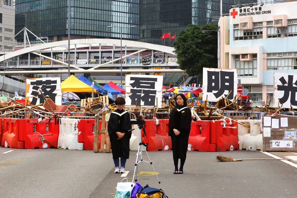 Graduates take photos on the blocked road in Admiralty protest site of the Occupy Central movement. Photo: Felix Wong