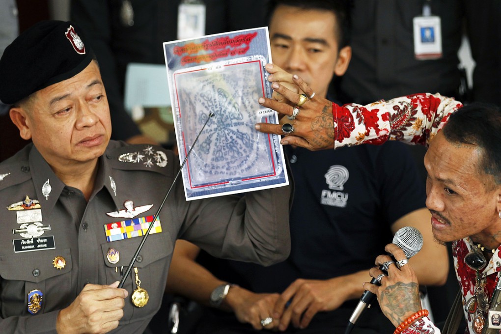 A tattoo expert and a policeman (left) point at one of the pictures of body parts found in parcels as they address reporters in Bangkok. Photo: Reuters