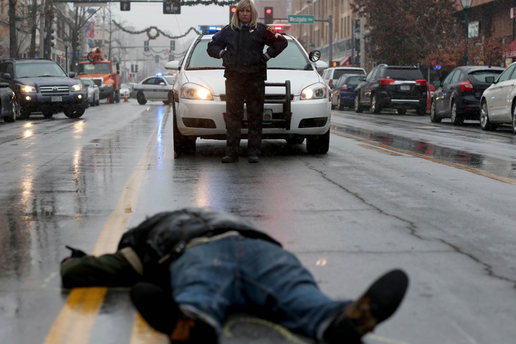 A police officer looks on as a demonstrator lays on the ground during a mock death protest of the shooting death of Michael Brown by a Ferguson police officer. Photo: AFP