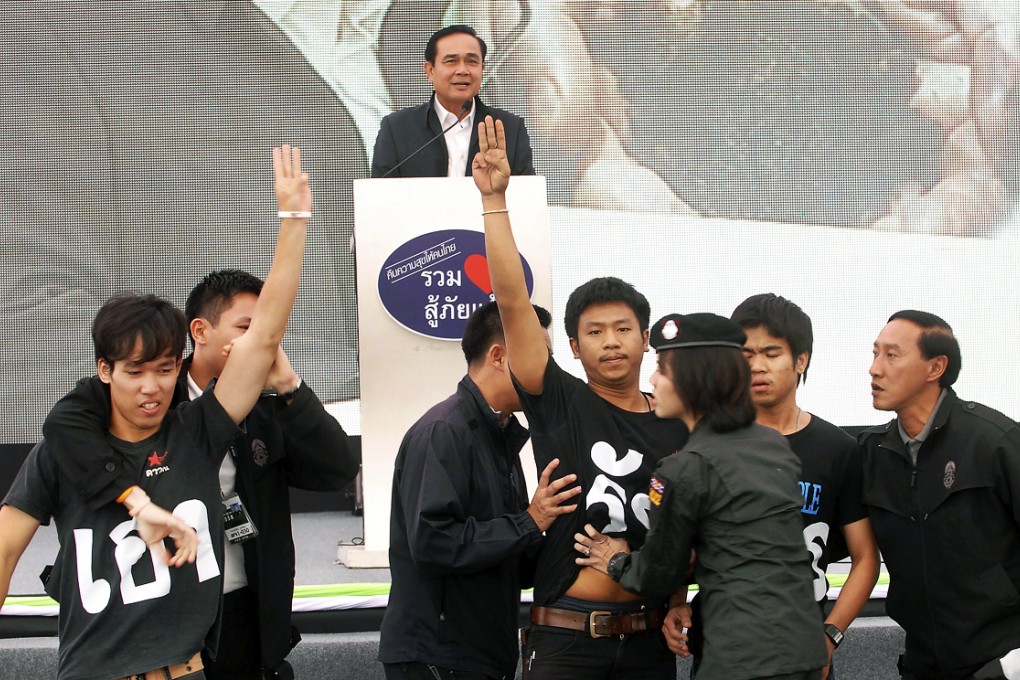 Thai student activists raise the three-fingered salute in front of Thai Prime Minister Prayuth Chan-ocha as he speaks in Khon Kaen, northeast of Bangkok. Photo: AP