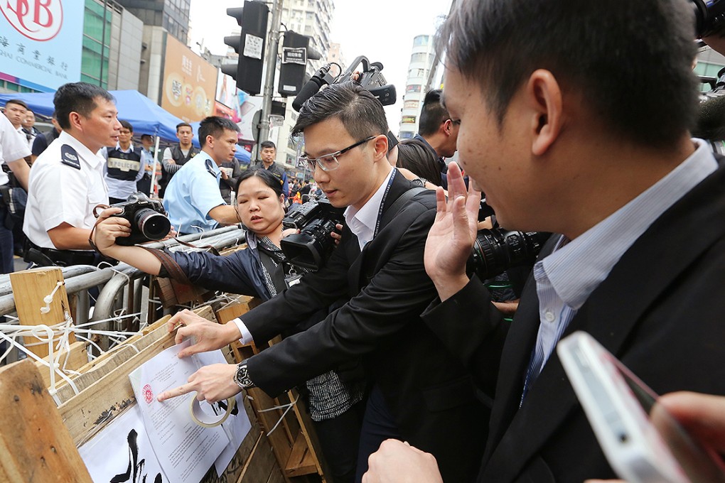 Legal representatives place a notice on a Mong Kok barricade set up by pro-democracy protesters, to be removed by bailiffs under a court injunction. Photo: Sam Tsang