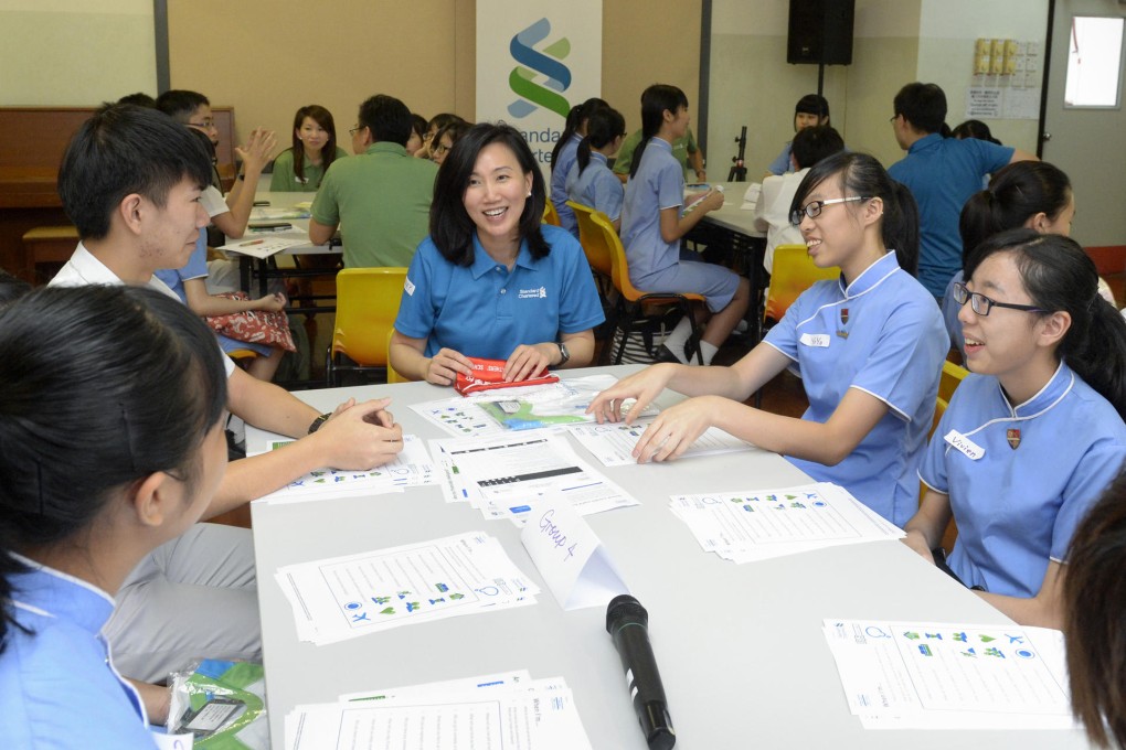Standard Chartered's Mary Huen (centre) guides students at a workshop designed to help them manage their finances.