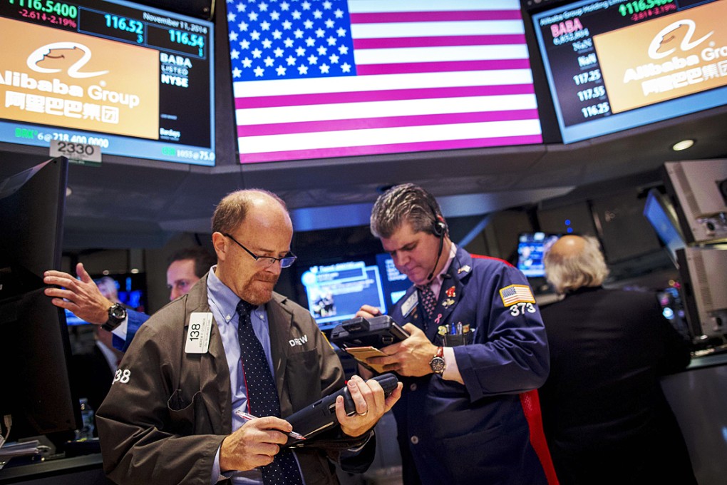 Traders in New York work near the post that trades Alibaba as the e-commerce behemoth received US$55 billion in orders for its dollar bond debut. Photo: Reuters