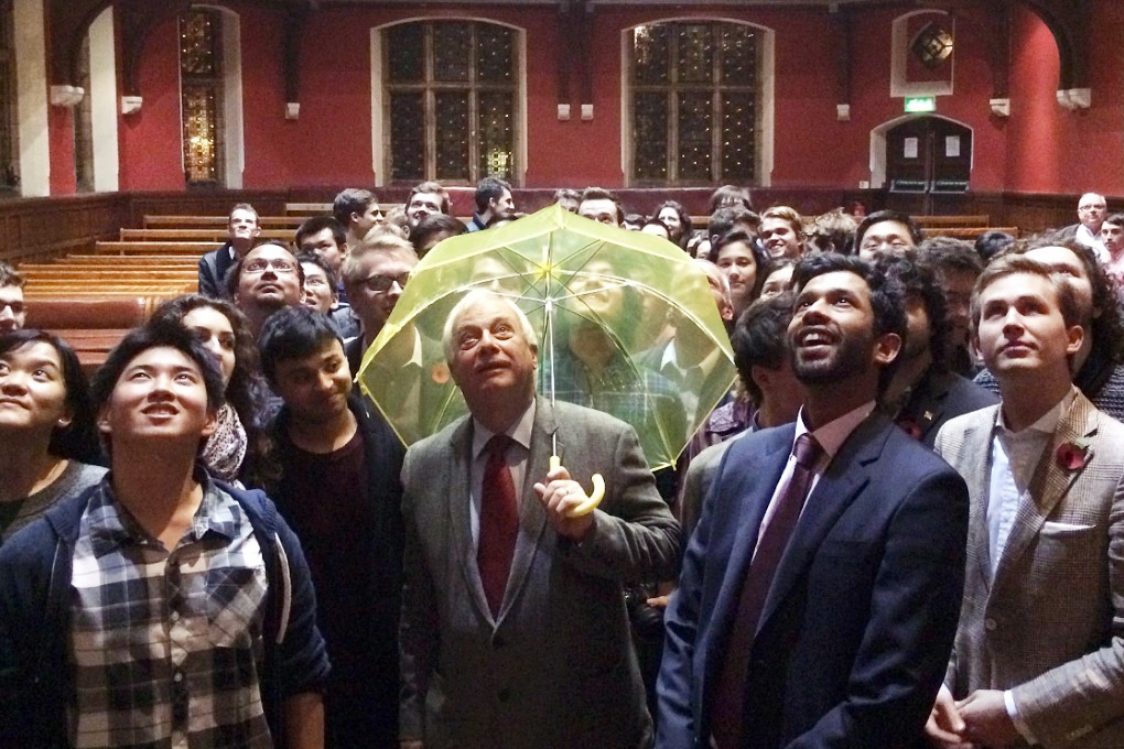In this picture taken on October 31, 2014, Hong Kong's last British governor Chris Patten, holds a yellow umbrella - a symbol of the Occupy movement in Hong Kong - after it was given to him by a University of Oxford student in the audience during an event at the Oxford Union in Oxford. Photo: AFP