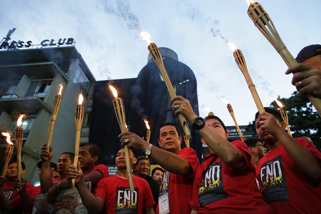 Journalists carry torches and display placards bearing the photos of victims of the massacre of 58 people, 32 of them journalists, as they march towards the Justice Department in Manila ahead of Sunday's 5th year commemoration of the massacre in Maguindanao, Southern Philippines. Photo: AP