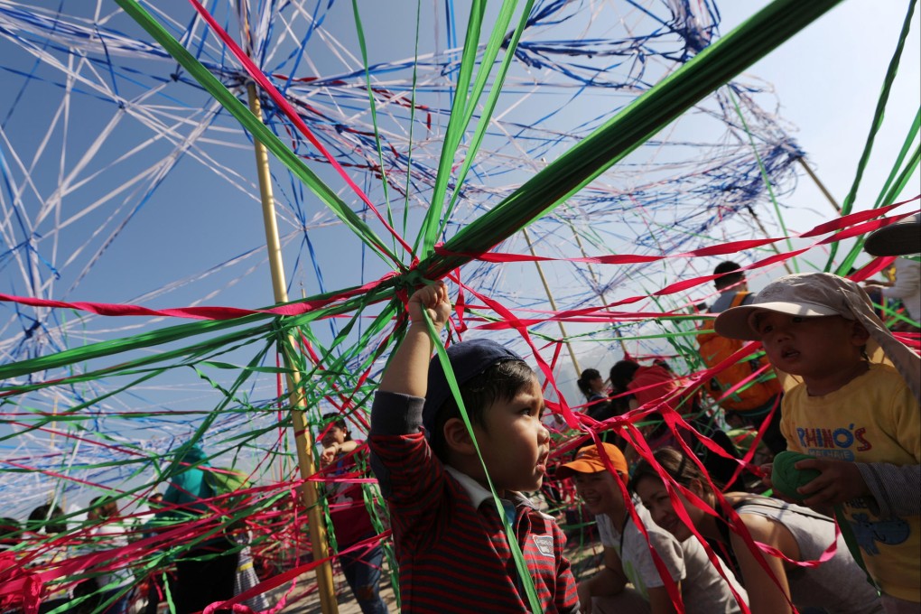Three-year-old Chun Chun helps spin a giant web as part of the Tangle installation by Australia's Polyglot Theatre. Photo: Sam Tsang