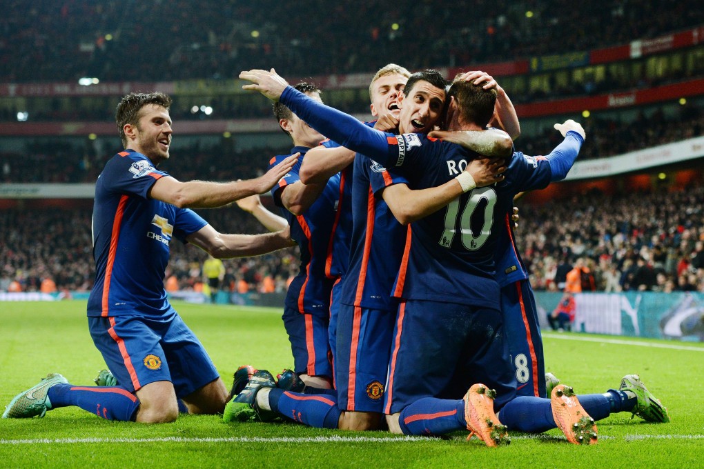 Wayne Rooney is hugged by his teammates after his decisive 85th-minute strike sealed Manchester United's 2-1 victory against Arsenal at the Emirates stadium. Photo: EPA