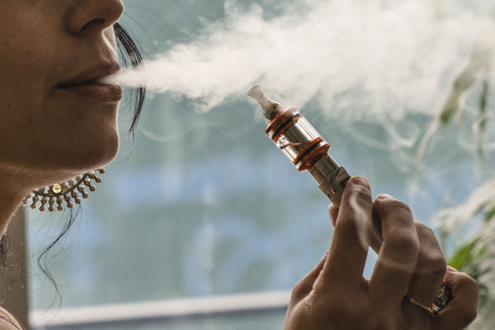 A woman uses a vaporizer, also known as an e-cigarette.