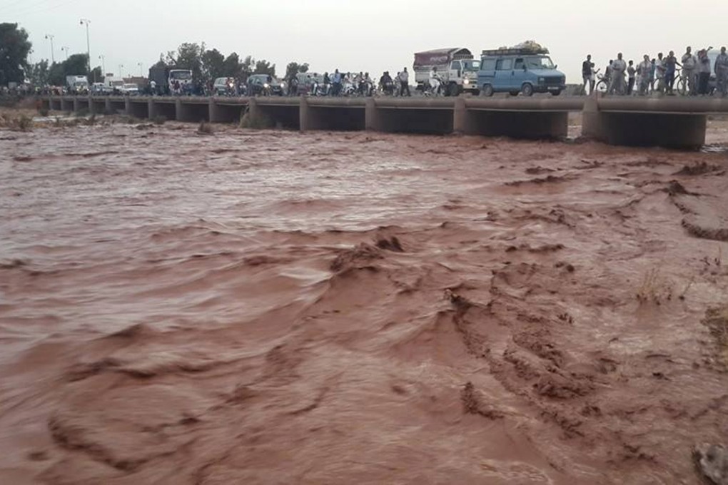 Residents of Guelmim cross a bridge over floodwaters.