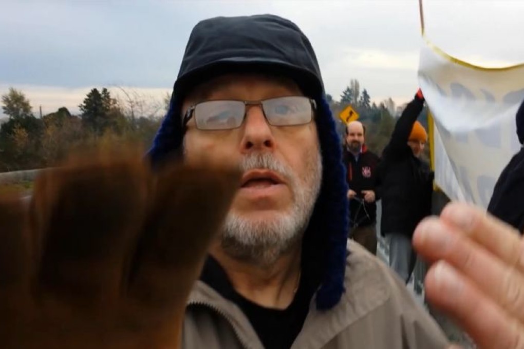 Immigration consultant Ray Primack reaches to snatch the phone out of the hand of Eron Main, who was filming a November 19 anti-immigration protest in Richmond. Also present are Brad Saltzberg in the orange hat, and Dan Murray (obscured) in the black hat. Photo: Handout
