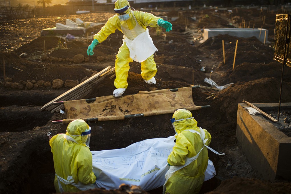 A burial team lowers the body of an Ebola victim into a grave in Freetown, Sierra Leone. Photo: The Washington Post