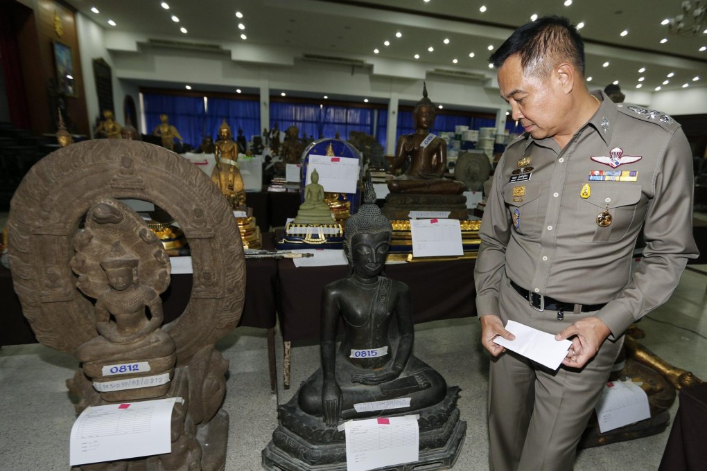 Police Chief Somyot Pumpunmuang inspects rare Buddha artifacts seized at the home of senior police officer Pongpat Chayapan. Photo: EPA