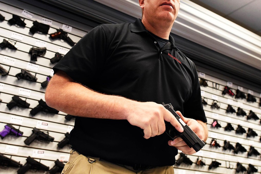 Paul Bastean, owner of the Ultimate Defense Firing Range and Training Center in St Peters, Missouri shows a handgun in his shop.  Photo: AFP