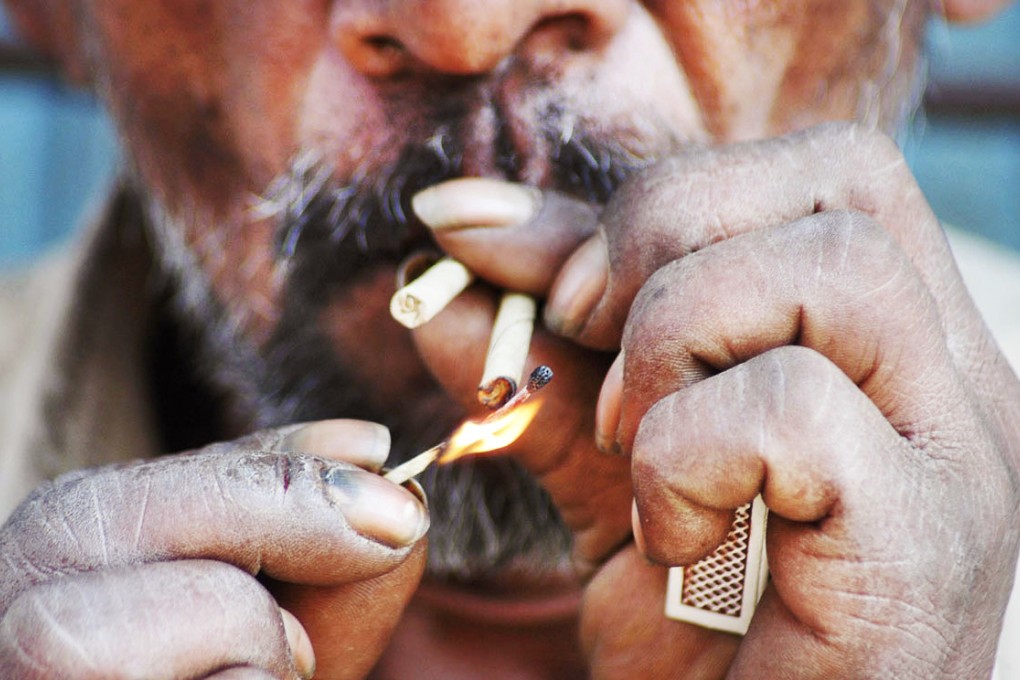 An Indian lights a cheaply made cigarette in Vadodara, India. Photo: AP