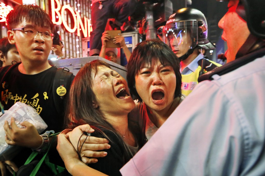 Protesters cry as officers try to stop them blocking the road in Mong Kok. Photo: AP