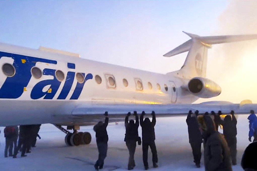The passengers were in a cheery mood as they pushed the plane onto the taxiway after its chassis froze.