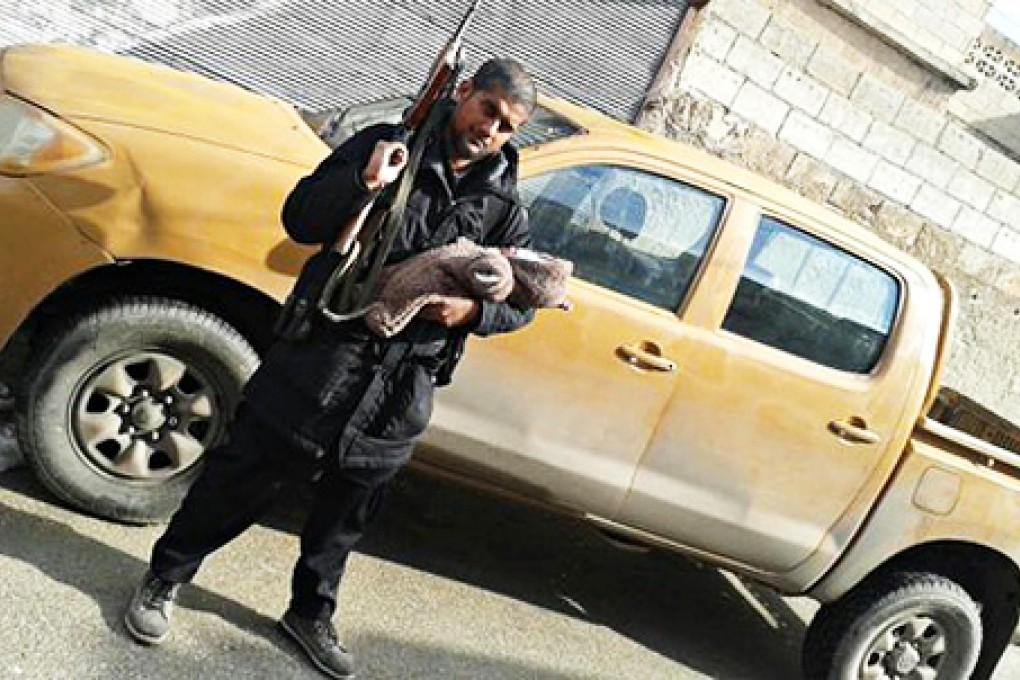 Siddhartha Dhar uploaded this image of him posing with a gun and his newborn baby boy in Islamic State-held area of Syria. Photo: Screenshot via Twitter